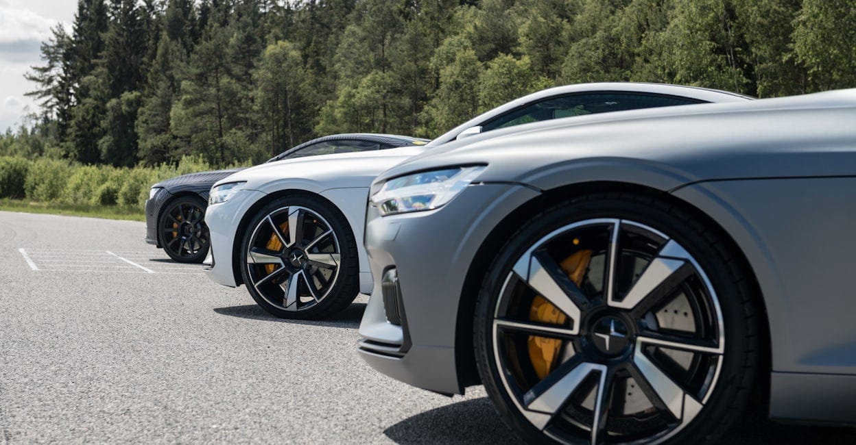 Three Polestar 1 cars parked in line on a forest road.