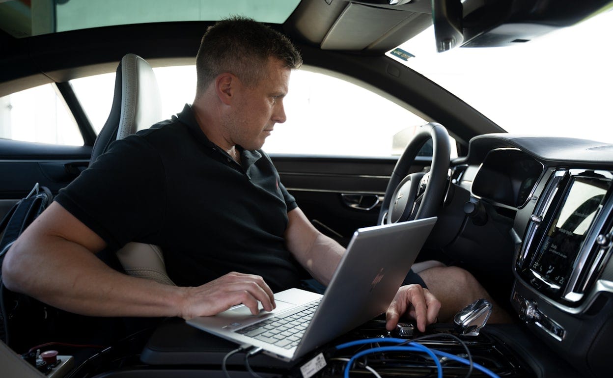 A man with a computer sitting in a Polestar 1