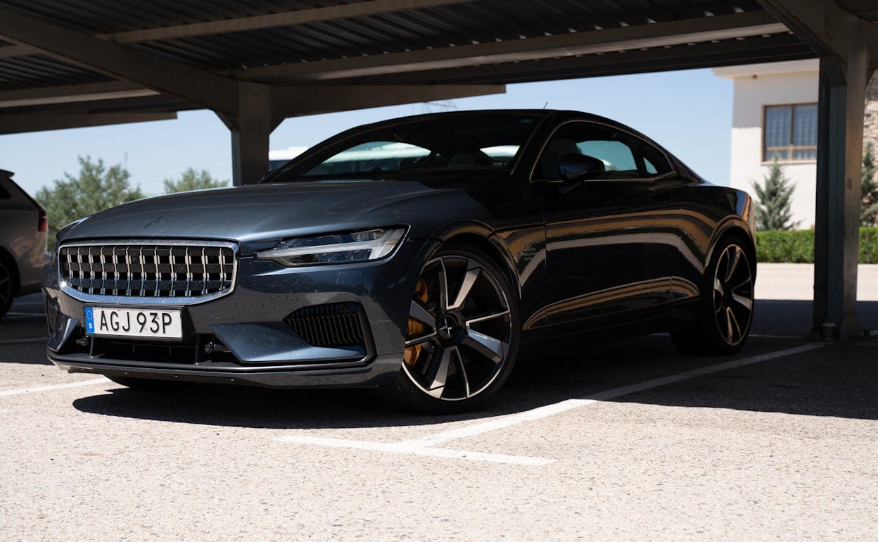 A Polestar 1 in the colour Black Midnight parked under a outdoor garage roof.