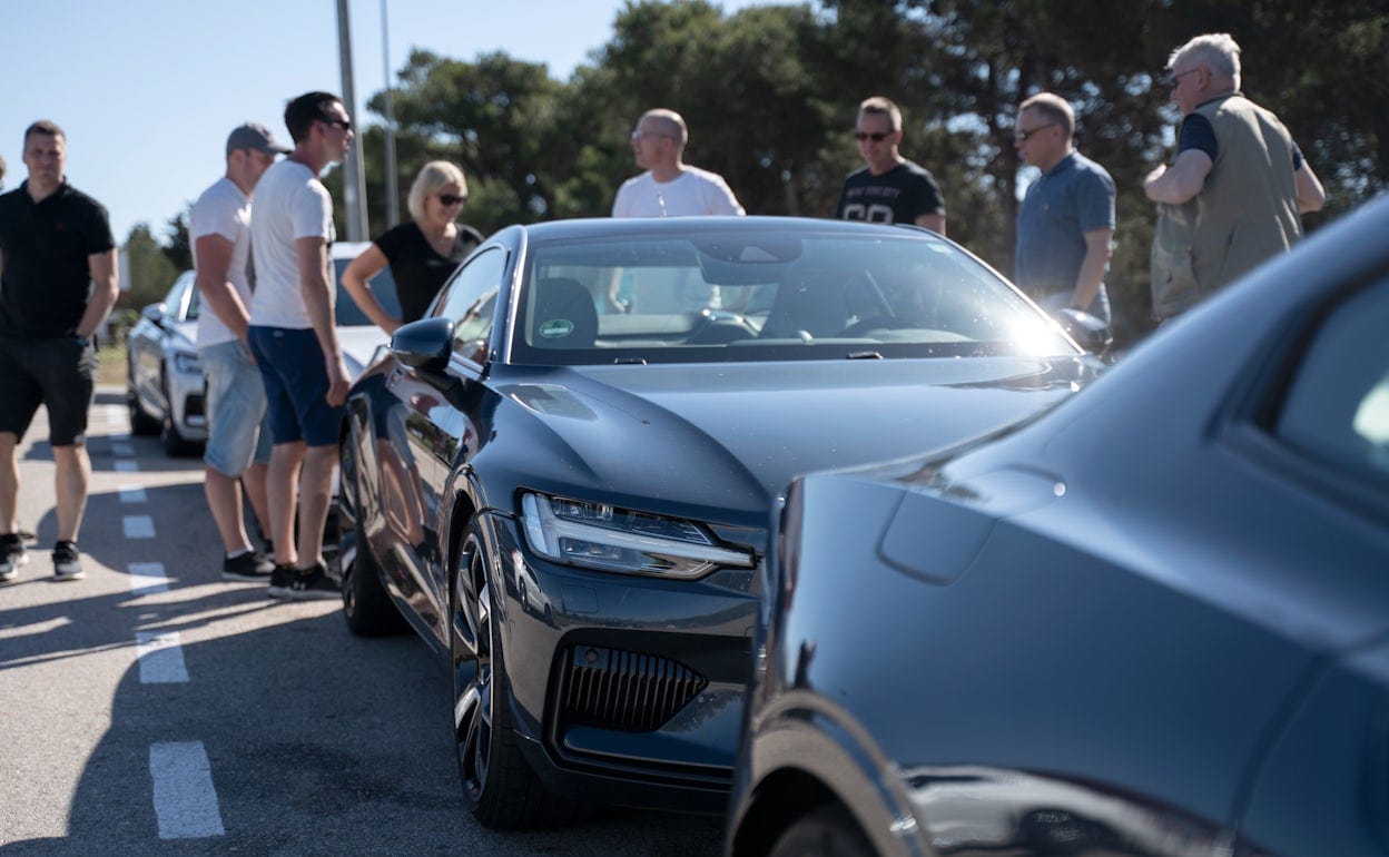 People inspecting a Polestar 1 parked on the side of a road.