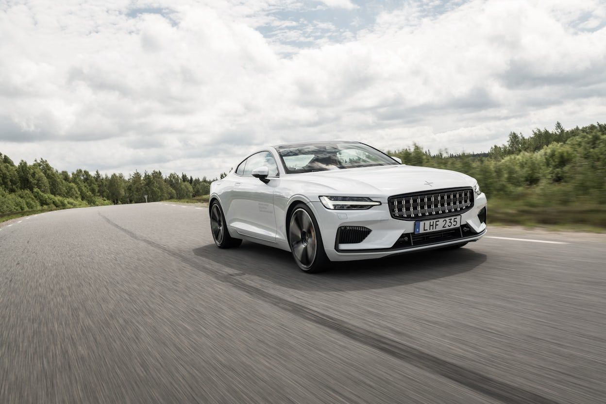 A white Polestar 1 driving on a forest road