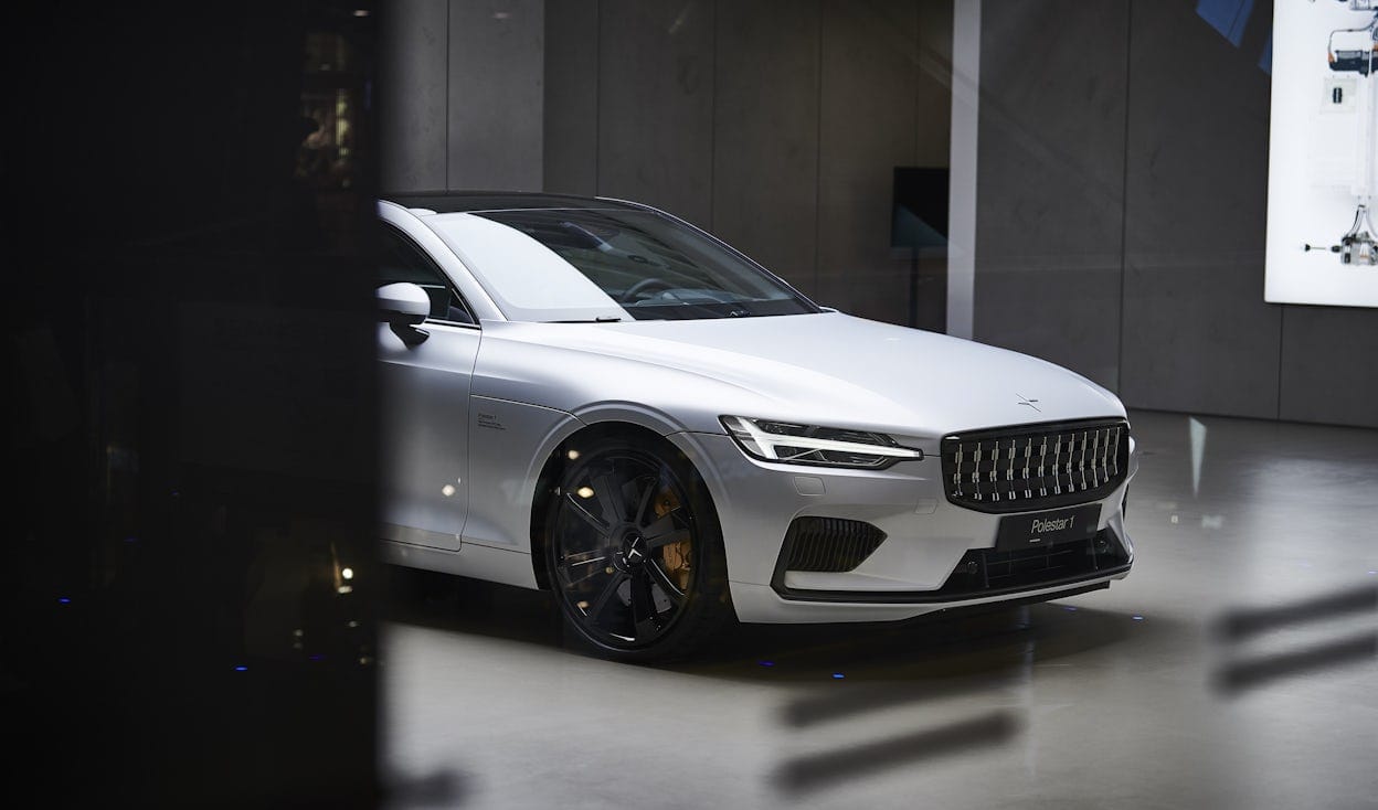 Front of a white Polestar 1 in a grey, minimalistic retail space.