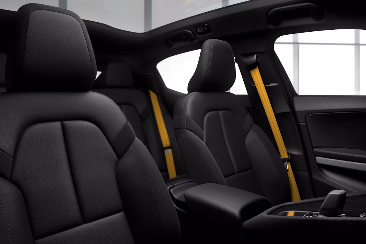 Black front seats of a Polestar 2 with the stereotypical Polestar golden seat belts.