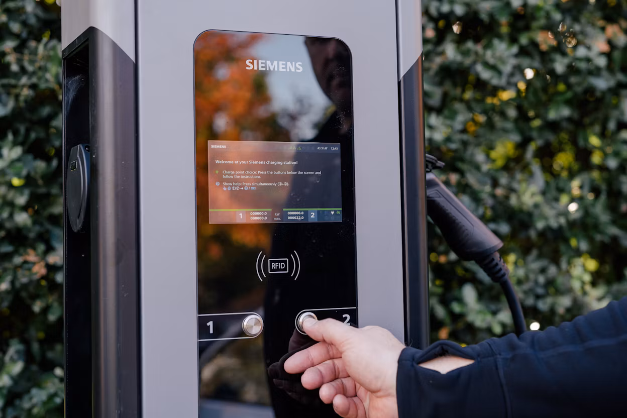 Hand pushing a button on a Siemens charging station.