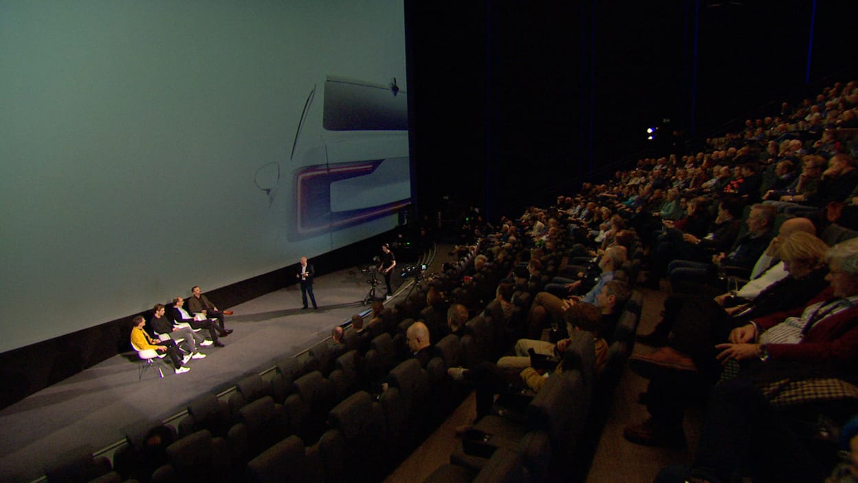 A seated audience listening to a panel discussion on the stage at Oslo’s Odeon Cinema.