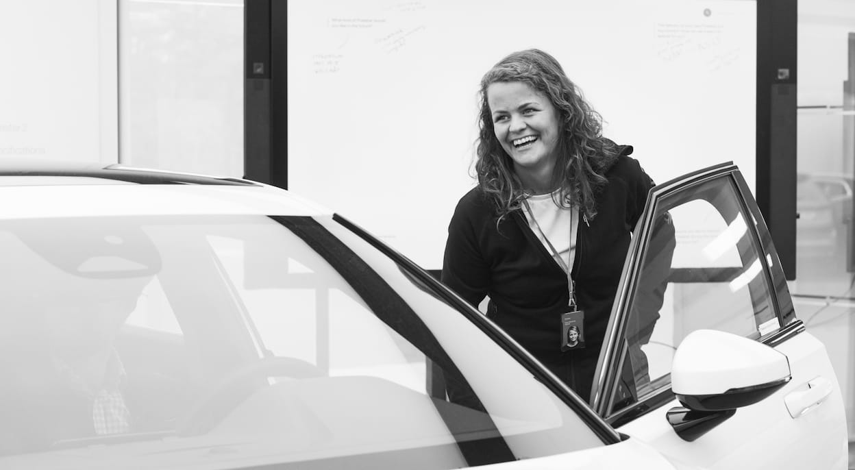 Smiling Polestar employee standing next to car with open front door