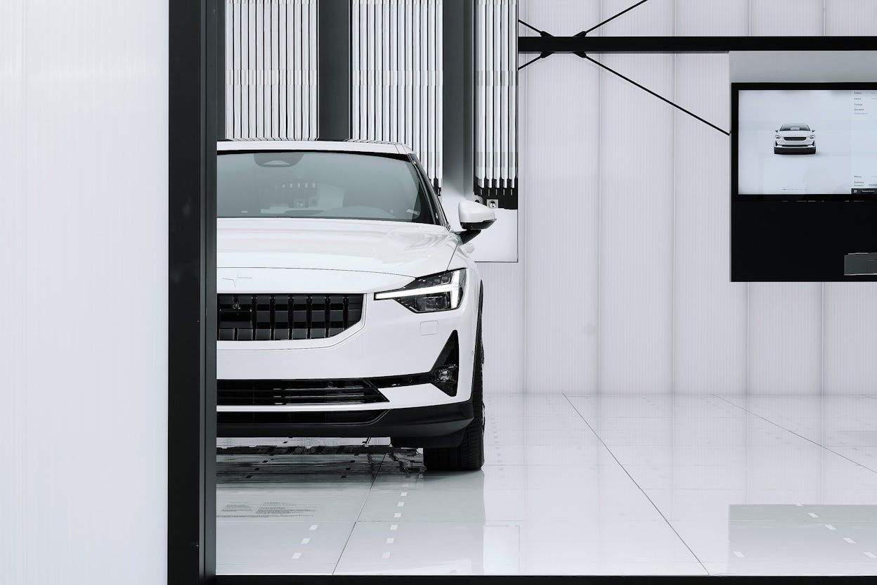 A white Polestar 2 in a exhibition space.