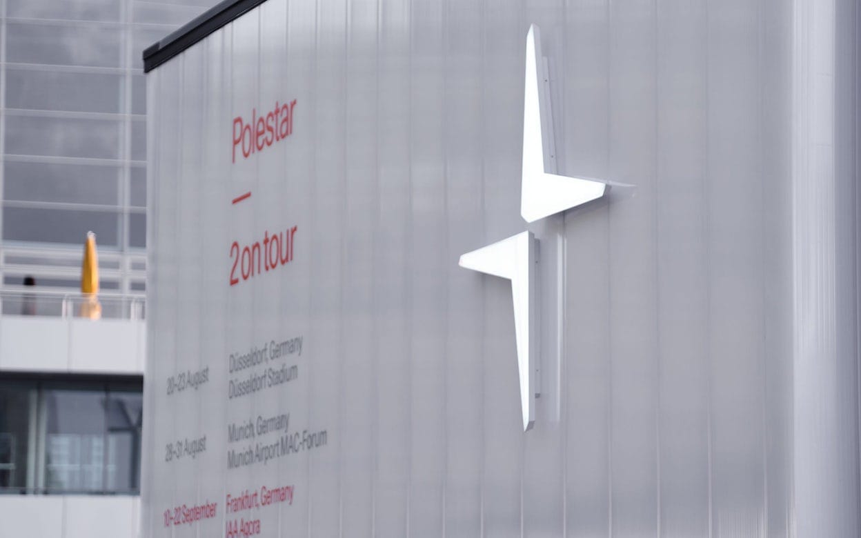 The Polestar logo on a white wall with text saying Polestar 2 on tour.