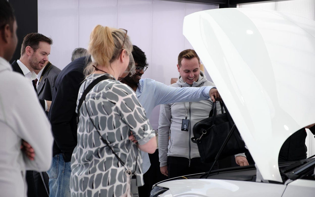 People inspecting a white Polestar 2 and putting a bag into the cargo compartment.