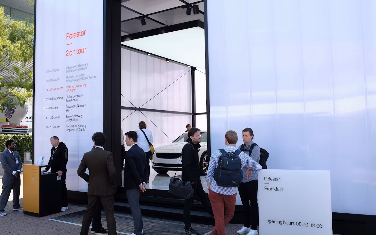 People standing outside a pop-up exhibition displaying a white Polestar 2.