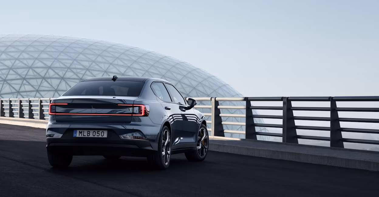 Back view of a Polestar 2 parked facing a fence with a glass globe and blue sky in the background.