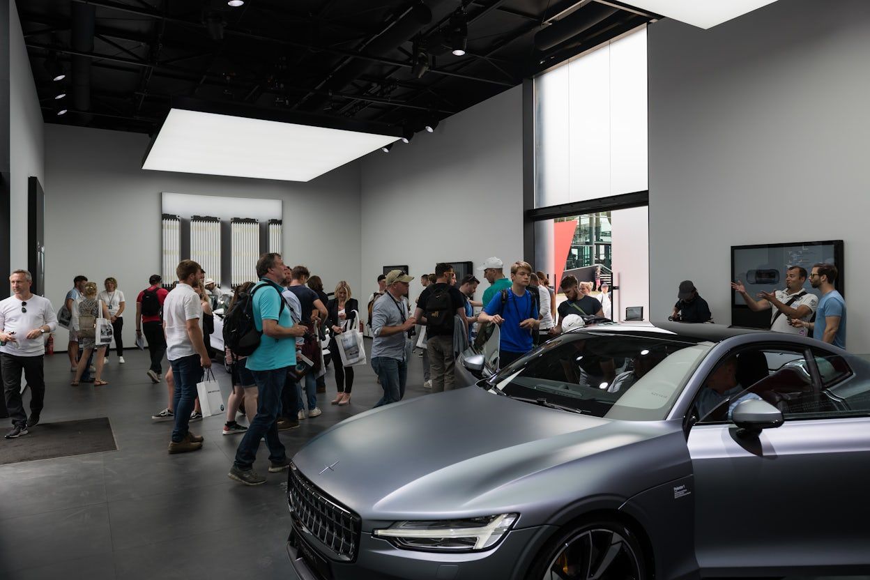 Visitors gathered around a metallic Polestar 1 showcased in a exhibition space at the Goodwood Festival