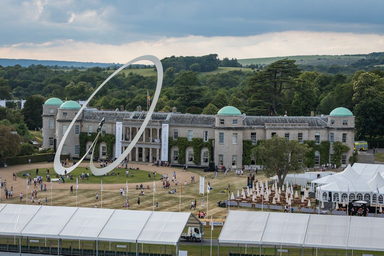 Goodwood House nestled amidst lush natural surroundings and event ground filled with people.