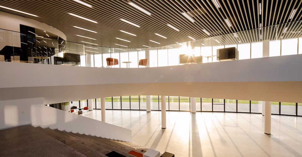 A grand staircase, the bottom floor and a balcony held up by white pillars surrounded by tall windows at the Polestar Production Centre in Chengdu.