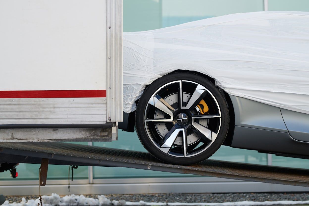 A Polestar 1 covered in white rolls out of a truck