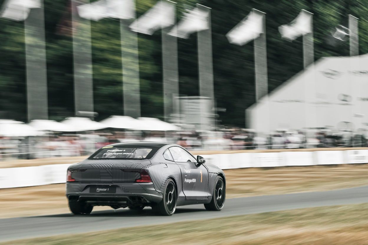 Back view of a Polestar 1 driving on a race track, with a blurry background.