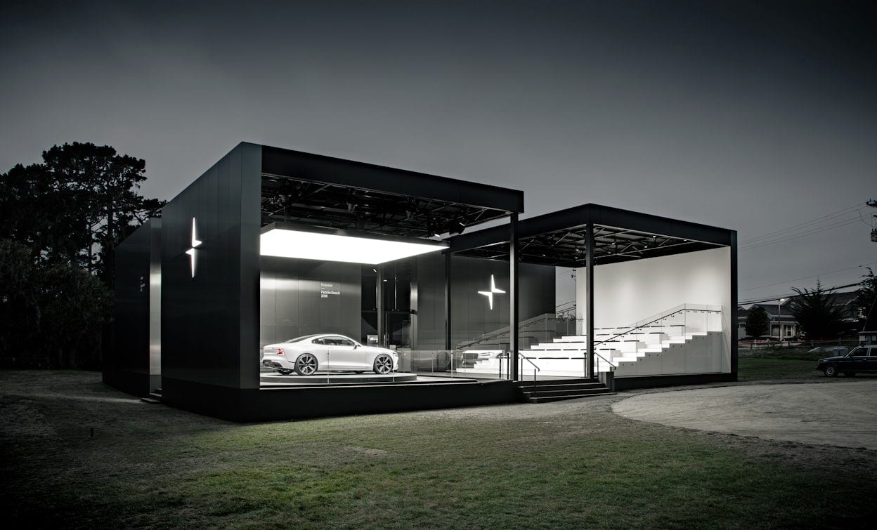 A black and white Polestar display on grass with a white Polestar inside photographed in the evening