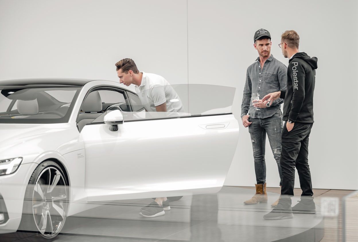 A person looking at the front seat of a white Polestar with the front door open