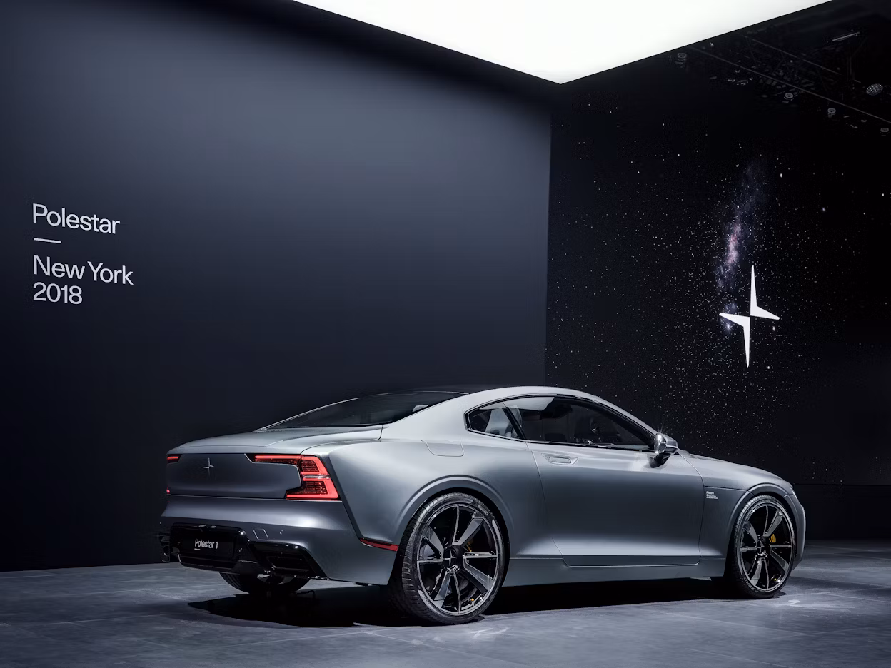 A silver Polestar 1 on display in front of a black wall with the text Polestar New York 2018.