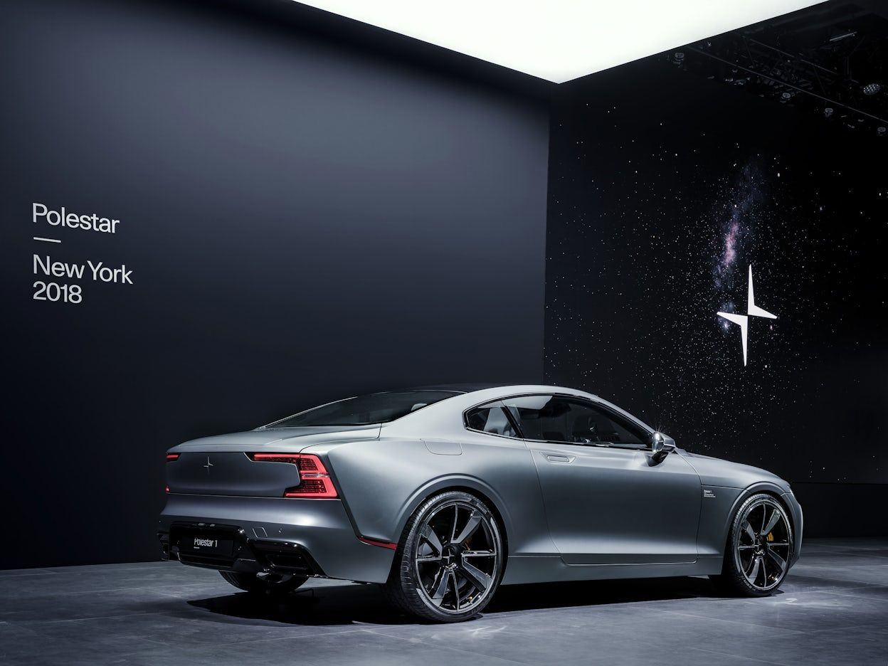 A silver Polestar 1 on display in front of a black wall with the text Polestar New York 2018.