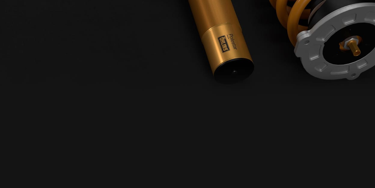 Öhlins adjustable, golden Dual Flow Valve dampers, displayed on a black background.