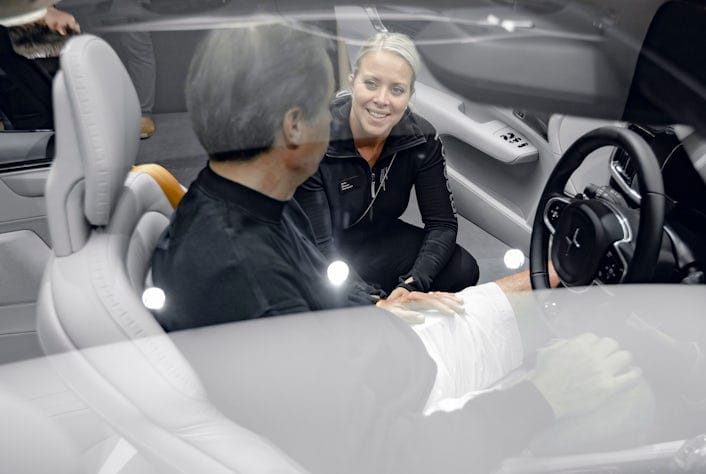 Man sitting behind the wheel of a Polestar talking to a woman kneeling next to the car.