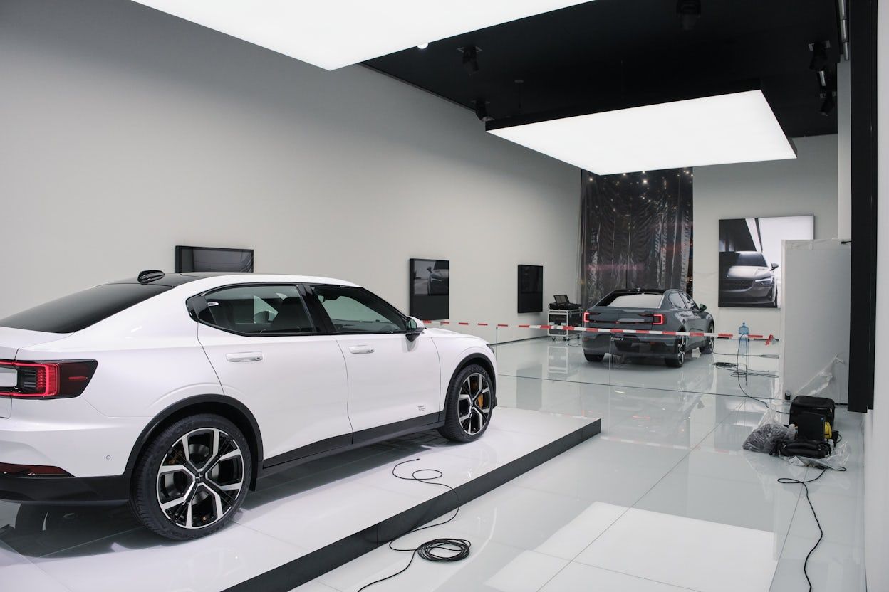 A Polestar space with a white and a black Polestar displayed on the white reflective floor.