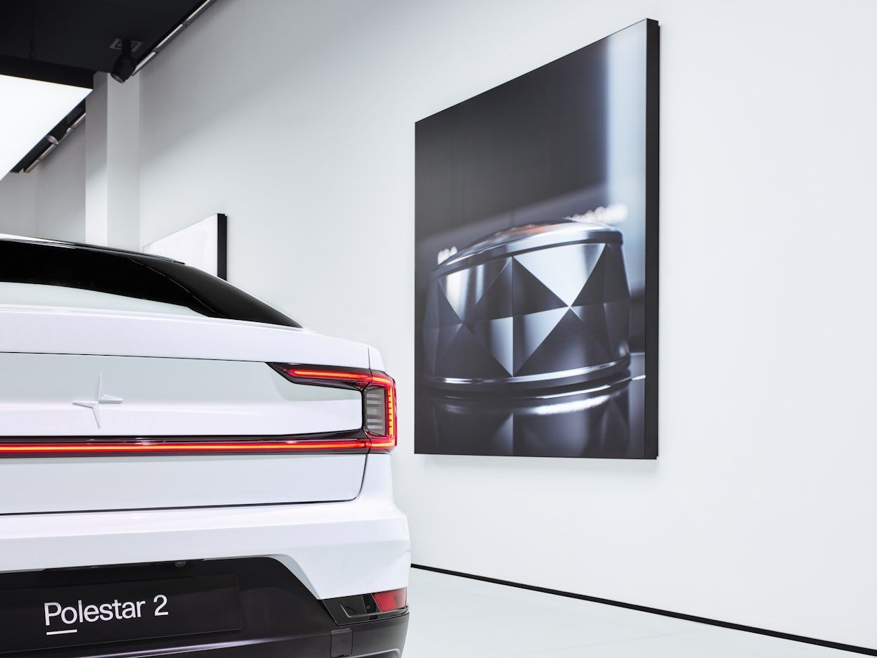 A white Polestar 2 viewed from behind in a white exhibition space.