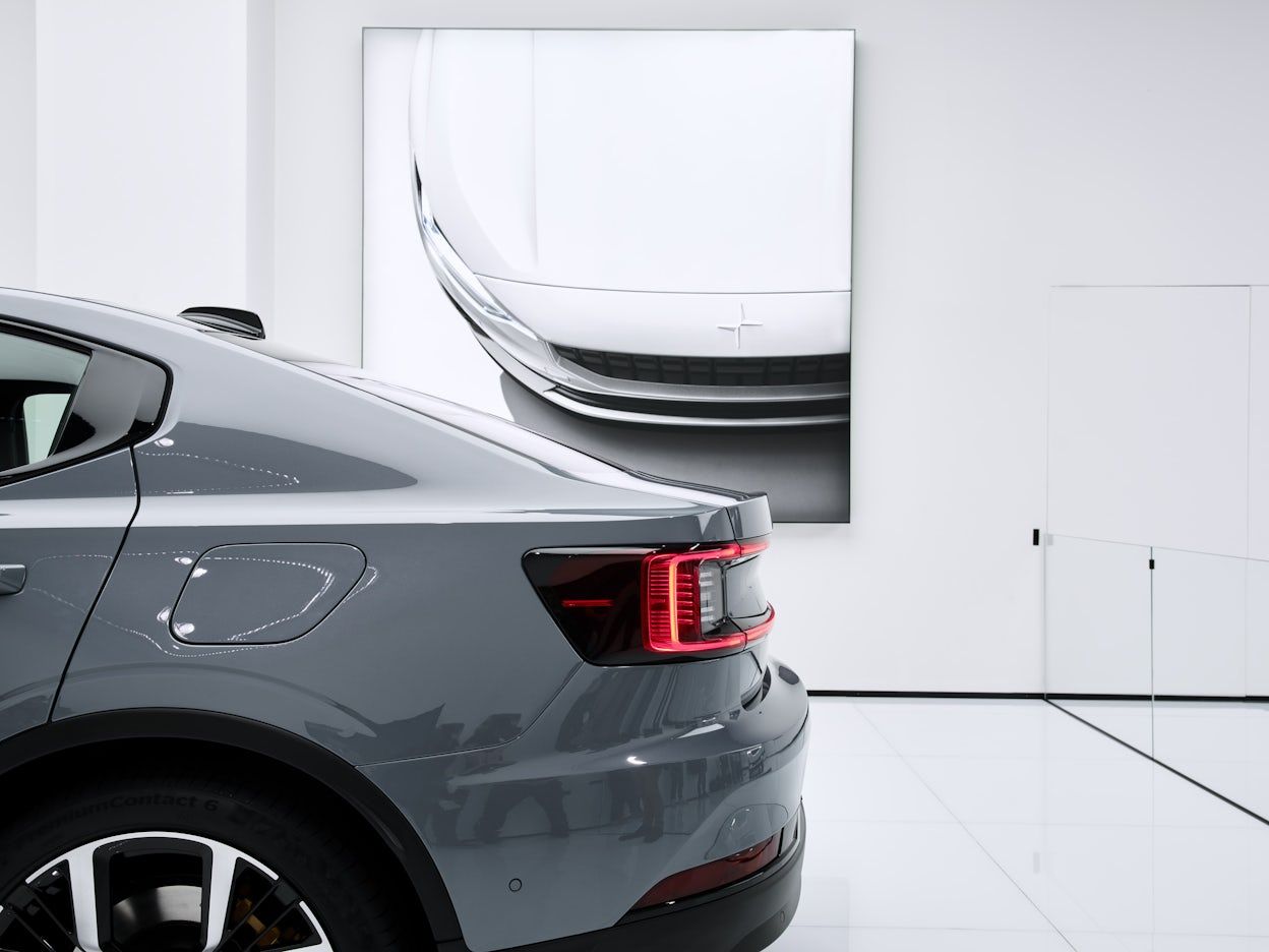 The back of a grey Polestar in a white room viewed from the side
