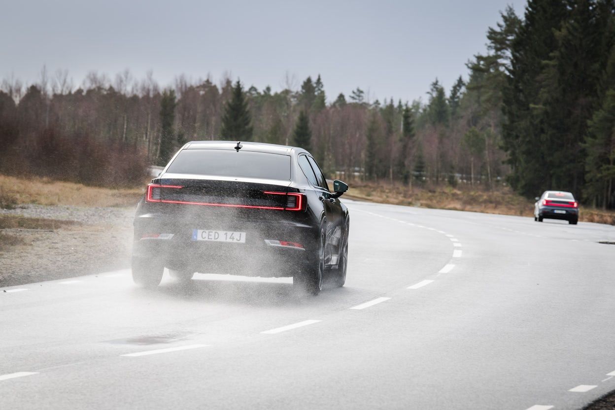 Back view of a black Polestar driving on a wet road.