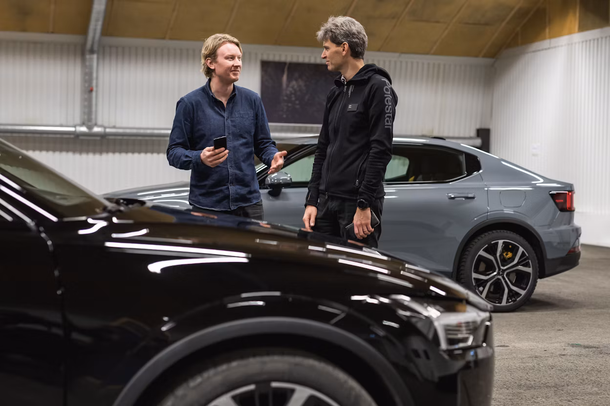 Two men talking between two parked Polestar car in a garage.