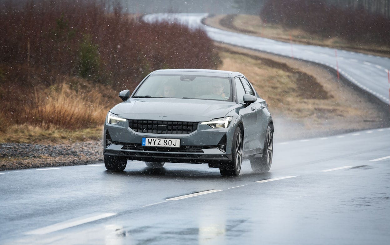 Front view of a grey Polestar 2 driving on a wet road.