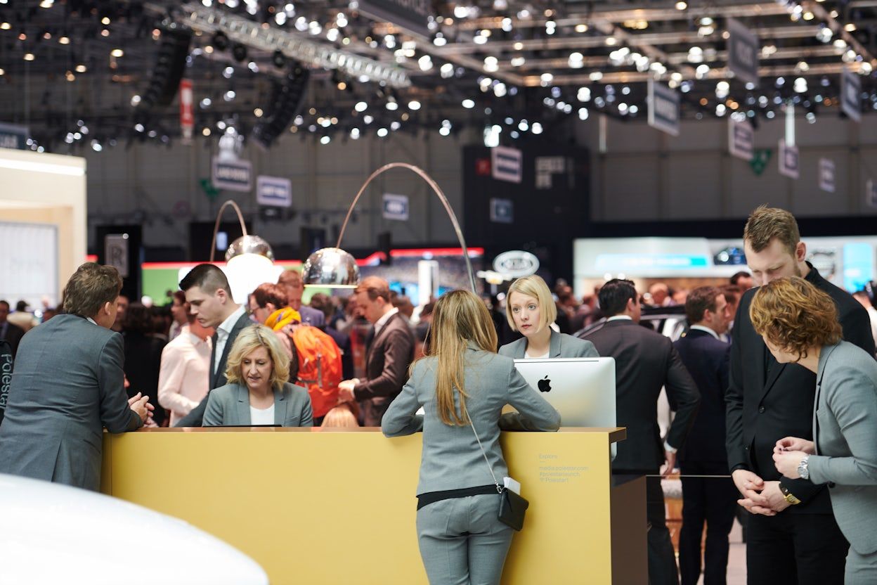 Crowd gathered around an information desk at the Geneva International Motor Show 2018.