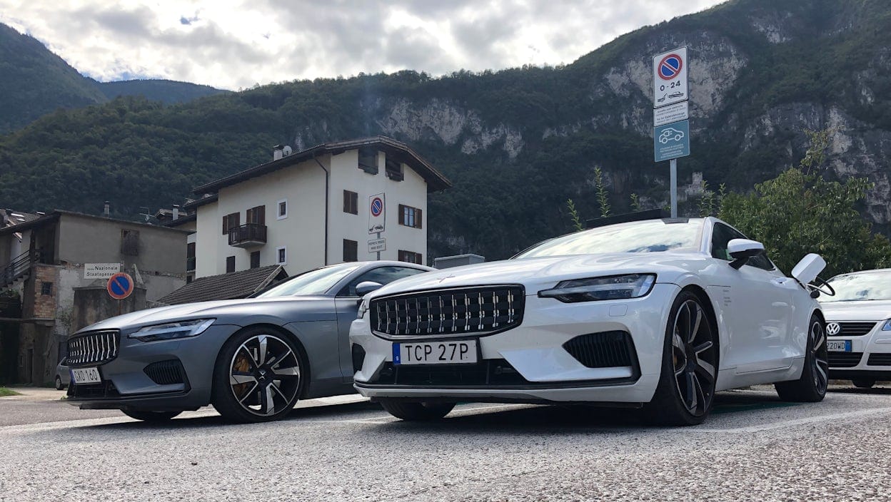 Front angle of two Polestar 1 cars positioned in the foreground of a scenic mountain landscape.
