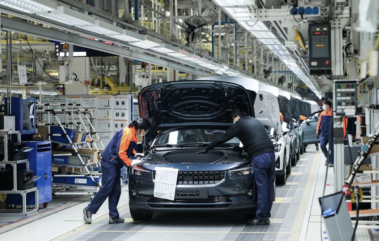 A long line of Polestar 2 in different colours being assembled on the production floor