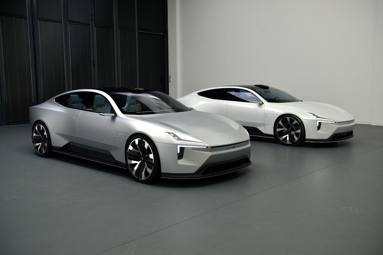 Two Polestar Precept, one grey and one white, parked in a empty warehouse.