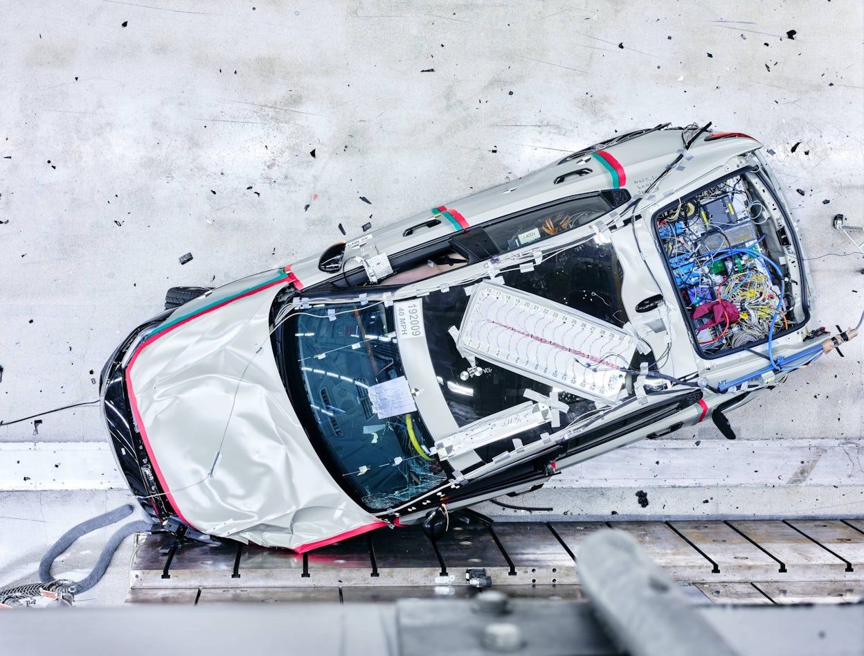 A Polestar 2 in the crash test tunnel with the front crashed into the wall, viewed from above.
