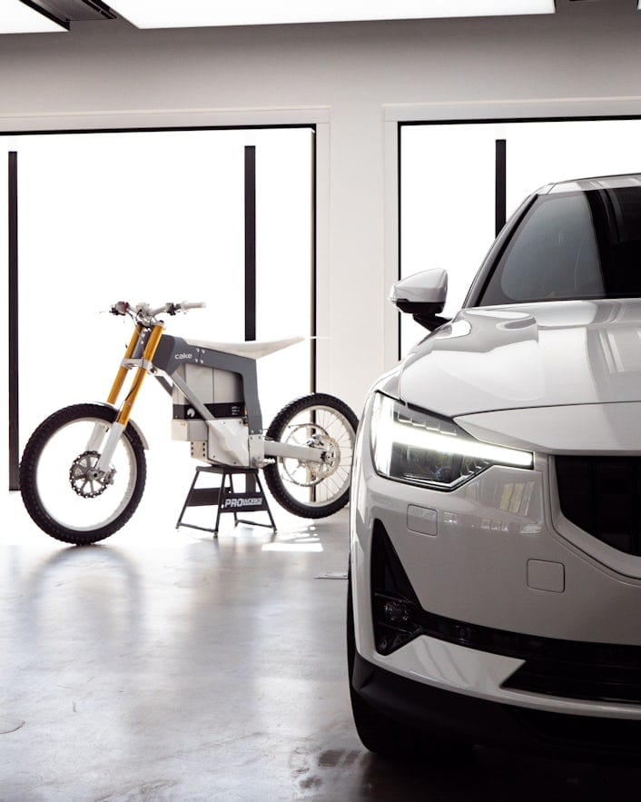 A CAKE electric off-road motorbike and a white Polestar in a room