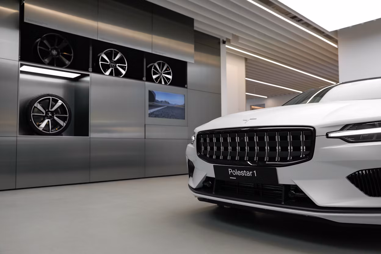 A white Polestar 1 in the Polestar Shanghai Space in front of metallic cabinets with wheels displayed inside.