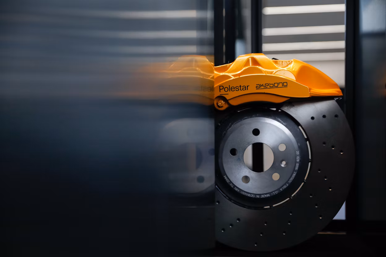 Close-up of orange breaks on a metallic car wheel.