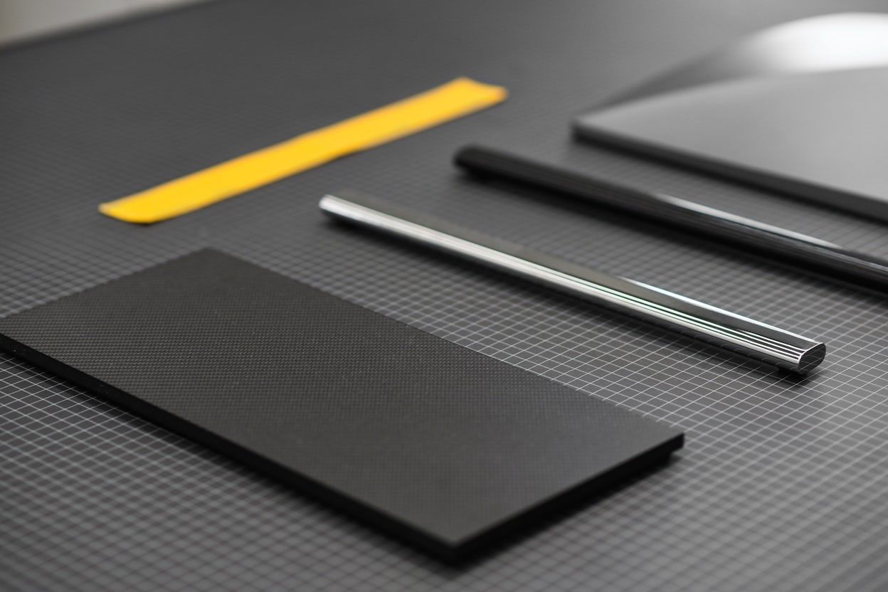 Two metallic rods and a black square and yellow piece of tape on a black surface