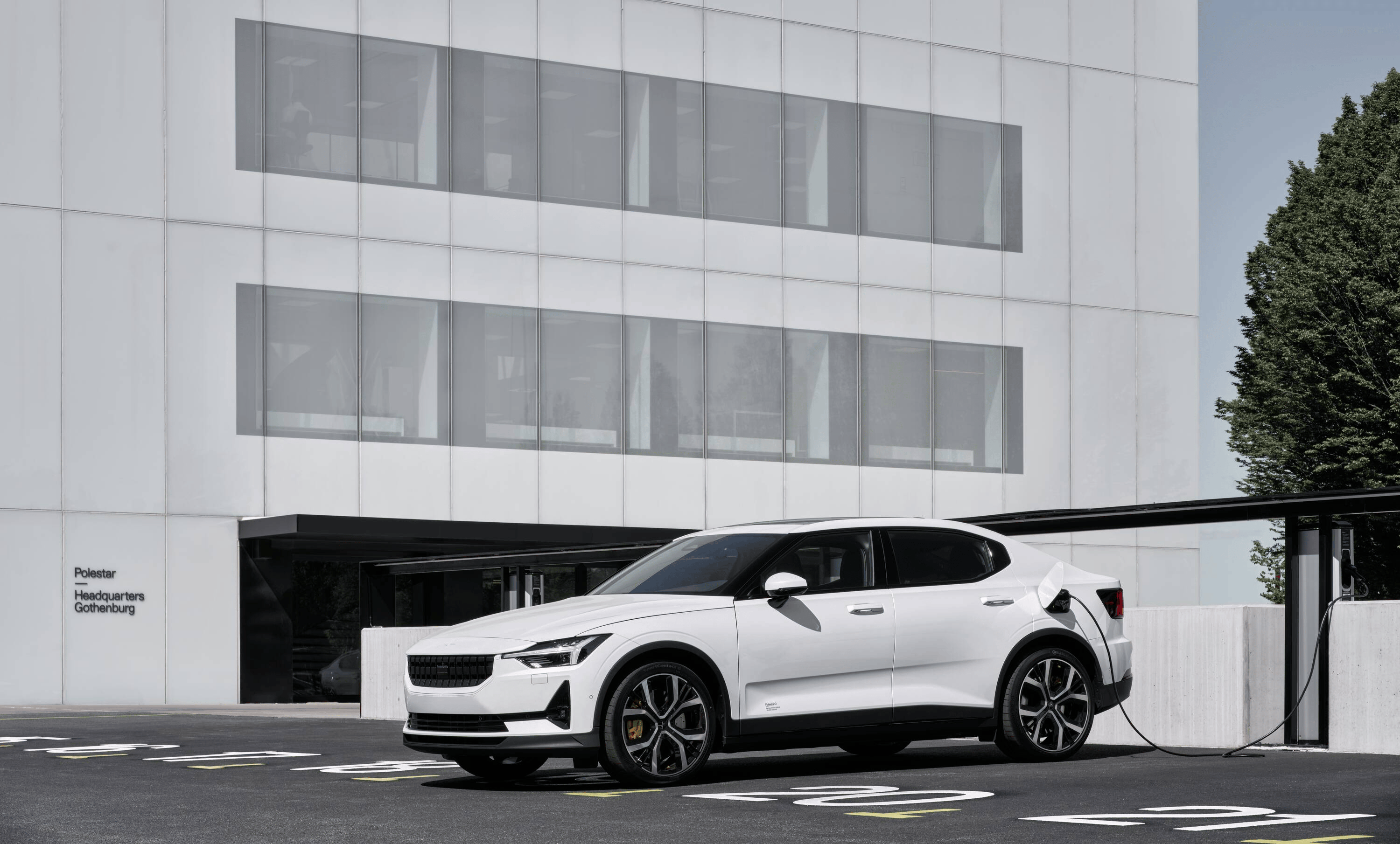 White Polestar 2 parked outside a white modern building while charging 
