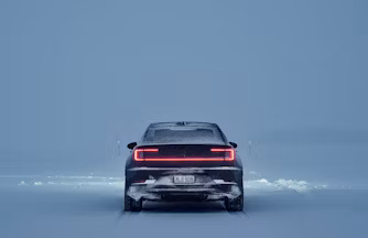 Black Polestar 2 from behind driving in a winter landscape