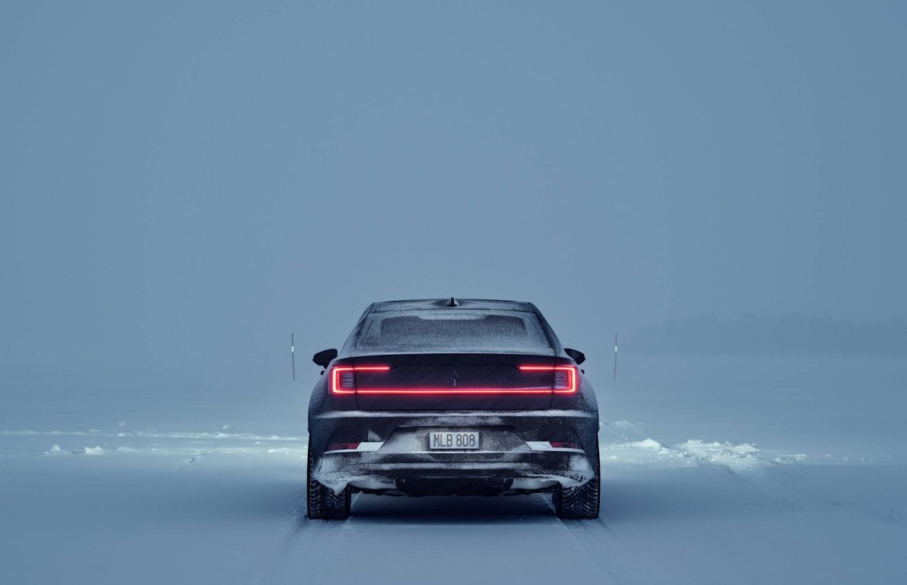 Black Polestar 2 from behind driving in a winter landscape 