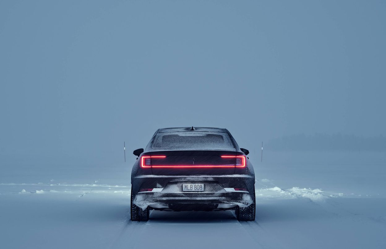 Black Polestar 2 from behind driving in a winter landscape 