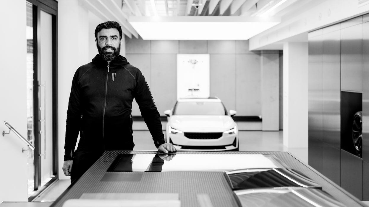 Asif Rana standing in front of a white Polestar photographed in black and white.