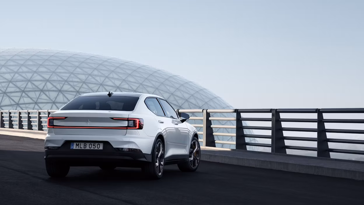 Back view of a white Polestar 2 parked in front of a railing.