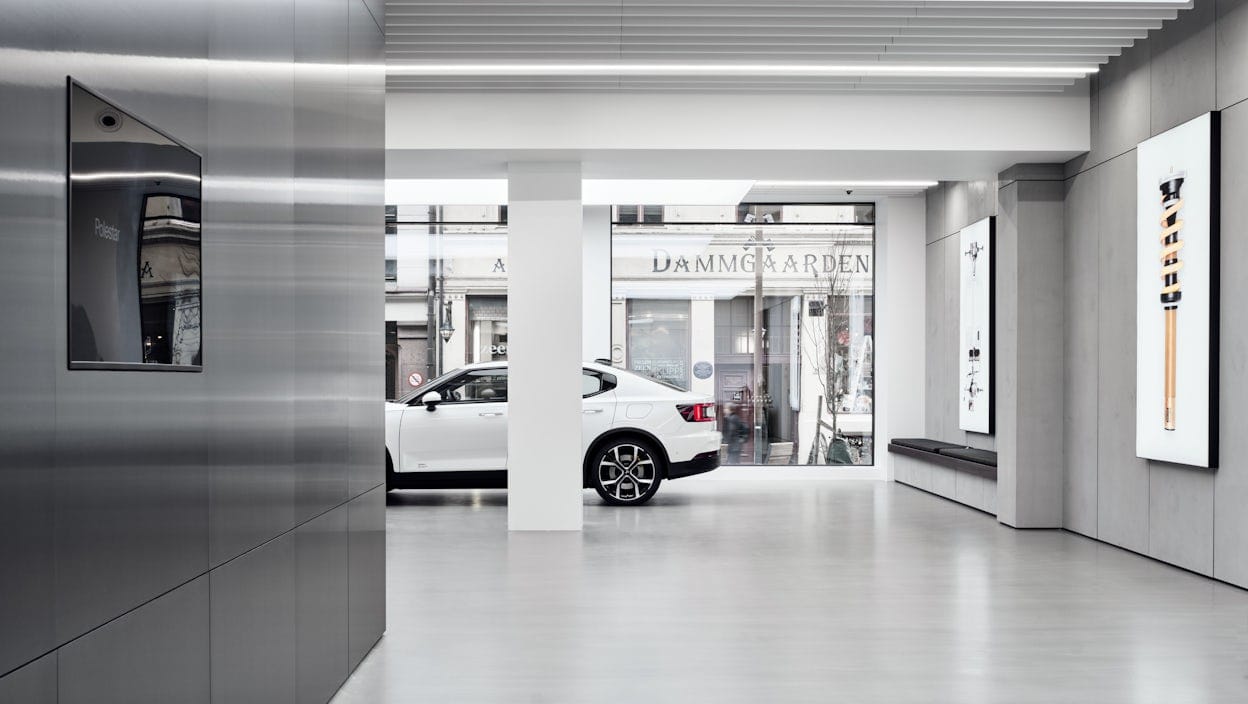 A white Polestar in a Polestar space with a city street visible through a large window.