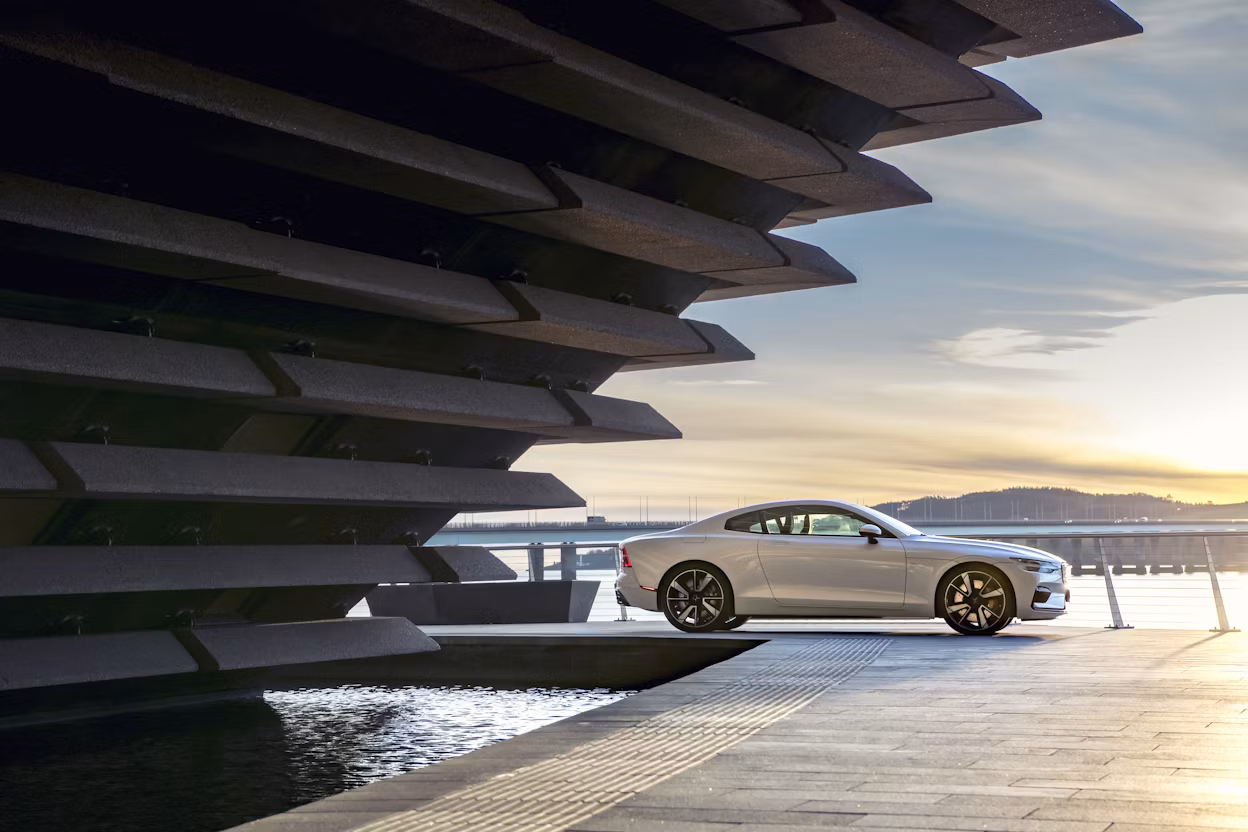 A white Polestar 1 parked in a port at sunset.