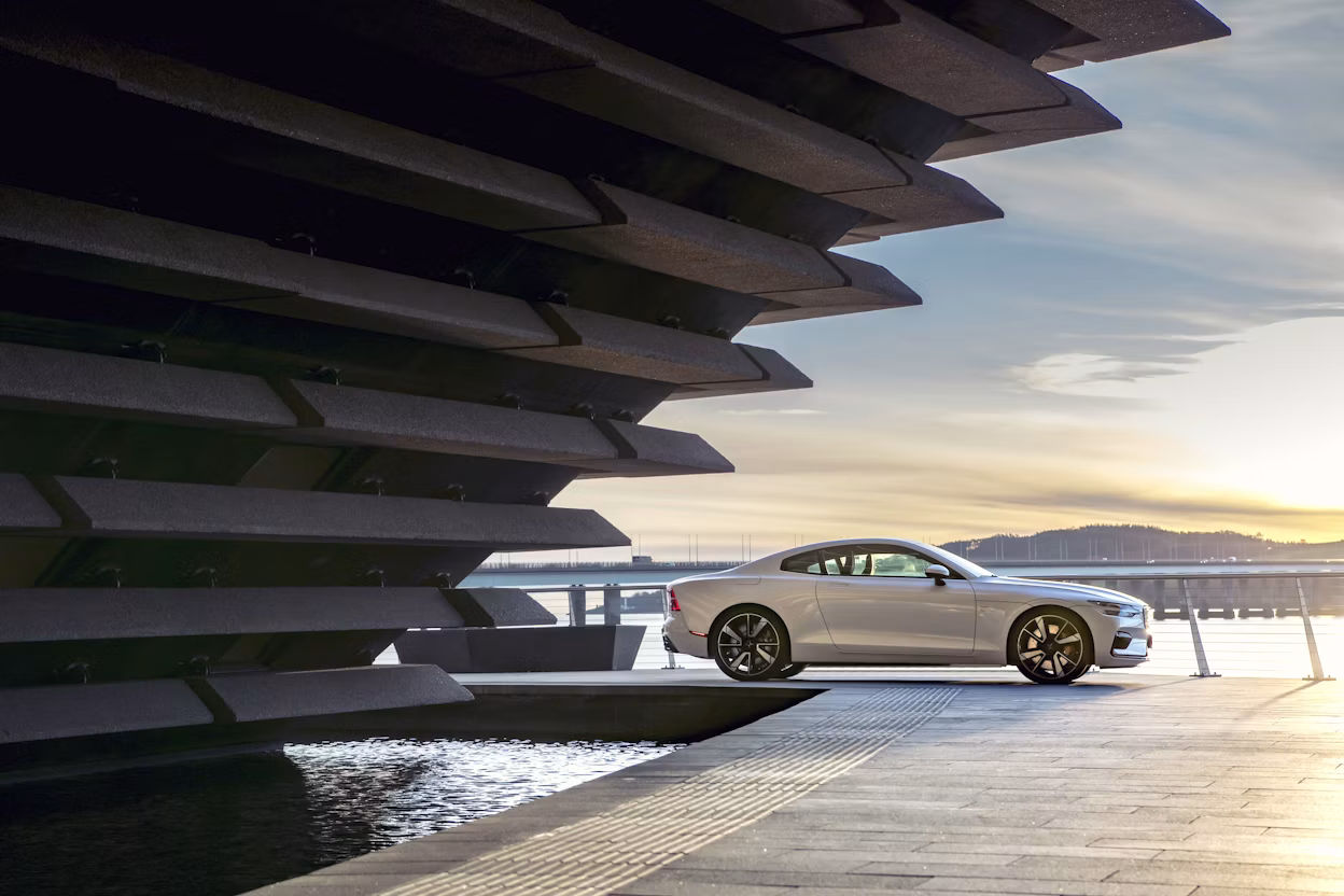 A white Polestar 1 parked in a port at sunset.